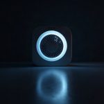 A generic bathroom ventilation fan unit on a glossy black surface with soft blue rim light.